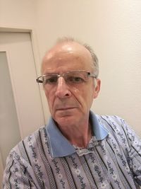 Portrait of man wearing eyeglasses against wall