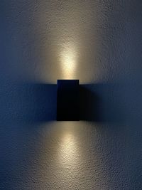 Illuminated electric lamp against wall