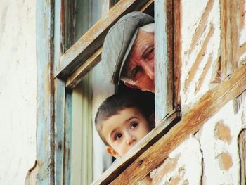 Portrait of grandfather and grandson looking through window