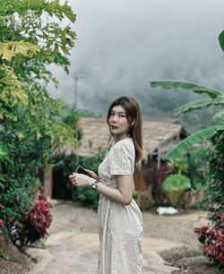 Young woman standing against plants