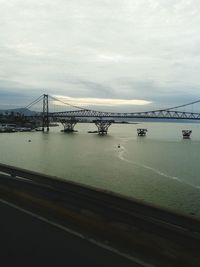 Bridge over river against cloudy sky