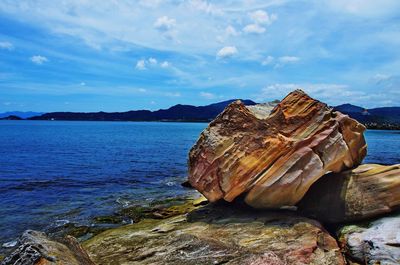 Rock formation by sea against sky