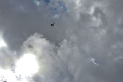 Low angle view of airplane flying against cloudy sky