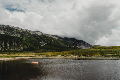 Scenic view of lake by mountains against sky