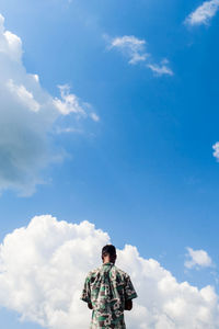 Low angle view of man standing against blue sky