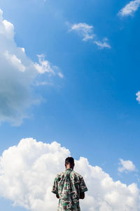 Rear view of man standing against blue sky