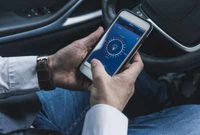 Man in car adjusting smart home device via smartphone