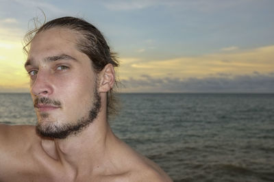 Portrait of shirtless young man against sea