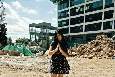 Young woman standing on sand at beach against sky