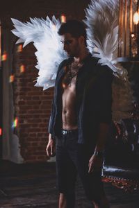 Young man wearing costume wings while standing indoors