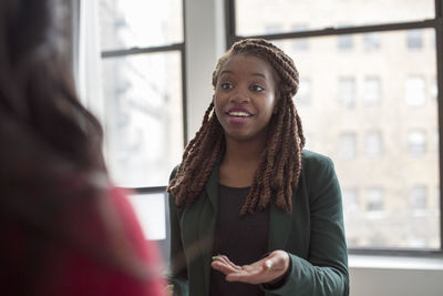 Businesswoman talking to colleague while standing in office