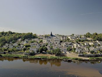 Scenic view of river by buildings against clear sky