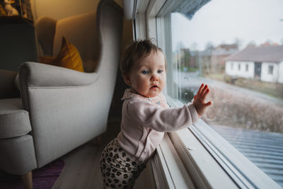 Baby girl standing in front of window