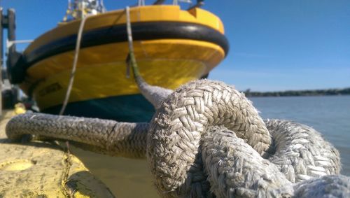 Close-up of rope tied to boat moored at harbor against clear sky