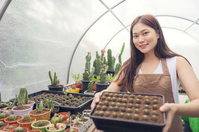 Woman looking at cactus in greenhouse garden center, asian young woman looking at small cactus