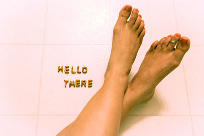 Low section of woman with hello there text on tiled floor