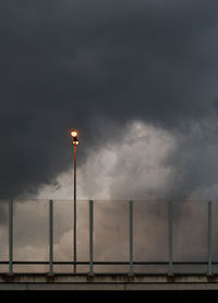 Low angle view of illuminated street light against cloudy sky