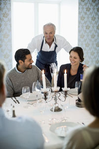 Senior chef talking to business people at dining table in restaurant