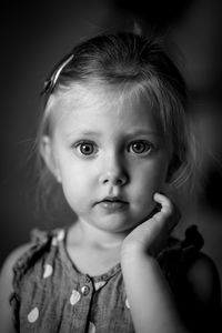 Close-up portrait of cute girl on black background