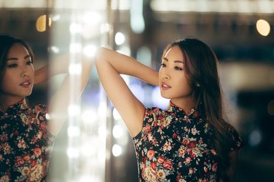 Beautiful young woman with arms raised at night