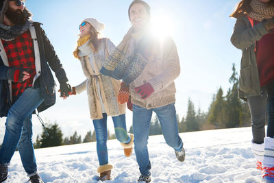 Friends running on snow covered landscape