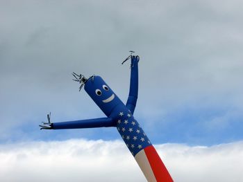 Low angle view of inflatable sculpture against cloudy sky