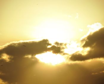 Low angle view of sun shining through clouds