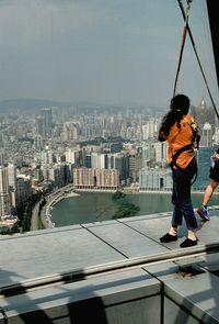 Side view of woman bungee jumping at macau tower against cityscape