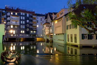 Buildings by river against sky in city at night