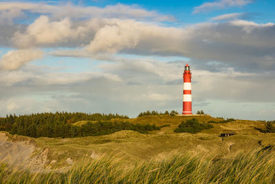 Lighthouse on field against sky