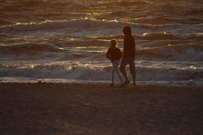 Man with daughter walking sandy beach