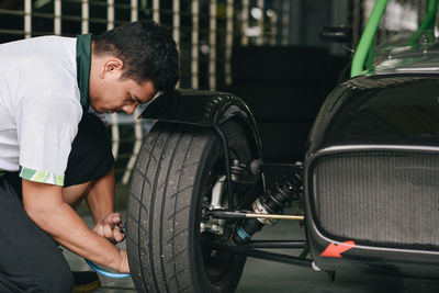 Side view of mechanic repairing car at garage