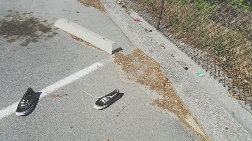 High angle view of shoes on footpath by fence