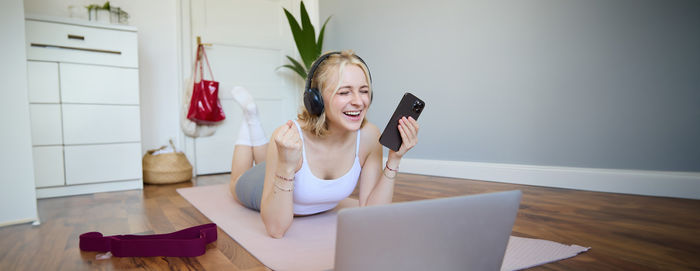 Portrait of young woman using mobile phone while sitting on table