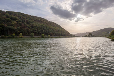 Scenic view of lake by mountains against sky