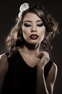 Close-up of beautiful young woman with brown hair against gray background