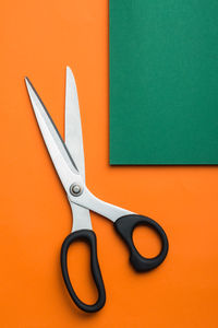 Scissors on green and orange cardboard background