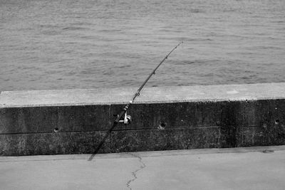 Fishing rod on retaining wall against sea