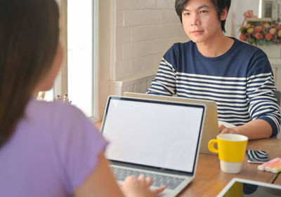 Young woman using phone while sitting on table