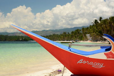 Boat moored on beach against sky