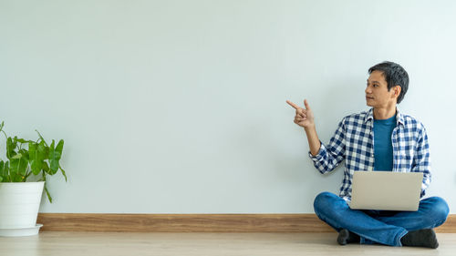 Full length of man using mobile phone while sitting on table