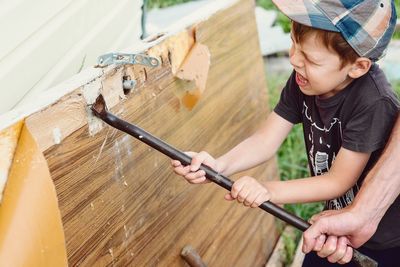 Pulling nails out of the board. strong boy face. 