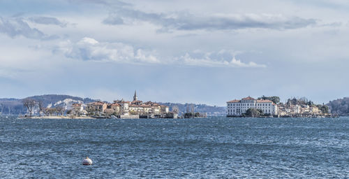 Buildings by sea against sky