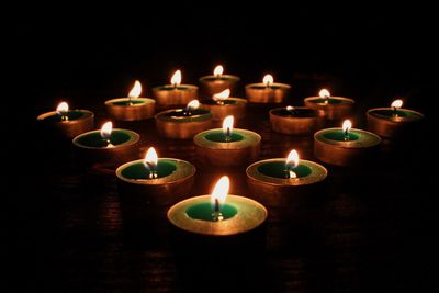 Lit tea light candles against black background