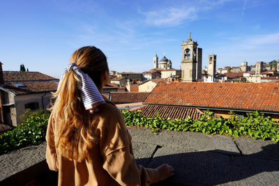 Rear view of girl looking the cityscape of bergamo, lombardy, italy