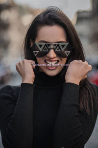 Portrait of young woman holding sunglasses