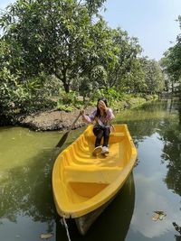 Young woman in boat on lake against trees