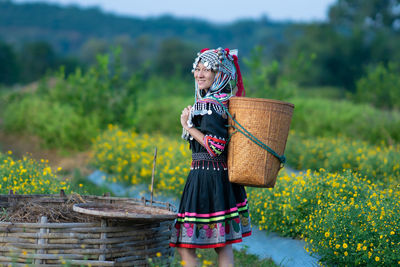 Woman holding umbrella while standing on field