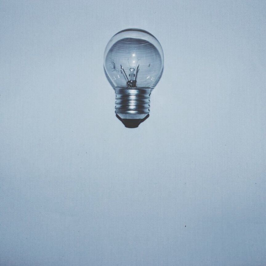 copy space, indoors, studio shot, white background, lighting equipment, close-up, low angle view, still life, glass - material, single object, electricity, wall - building feature, hanging, transparent, no people, light bulb, white color, simplicity, electric light, electric lamp