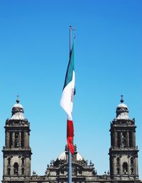 Mexican flag by metropolitan cathedral against clear blue sky